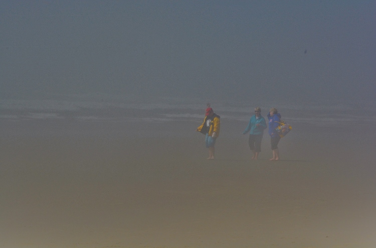 people on beach in fog barely seen
